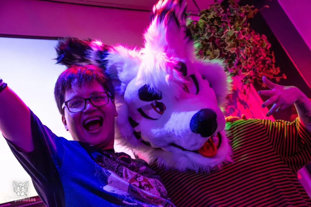 A happy person posing with a coyote fursuiter